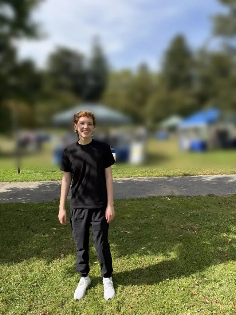 Zachary Penan smiling on the lawn at the Walkathon, with event tents in the background.