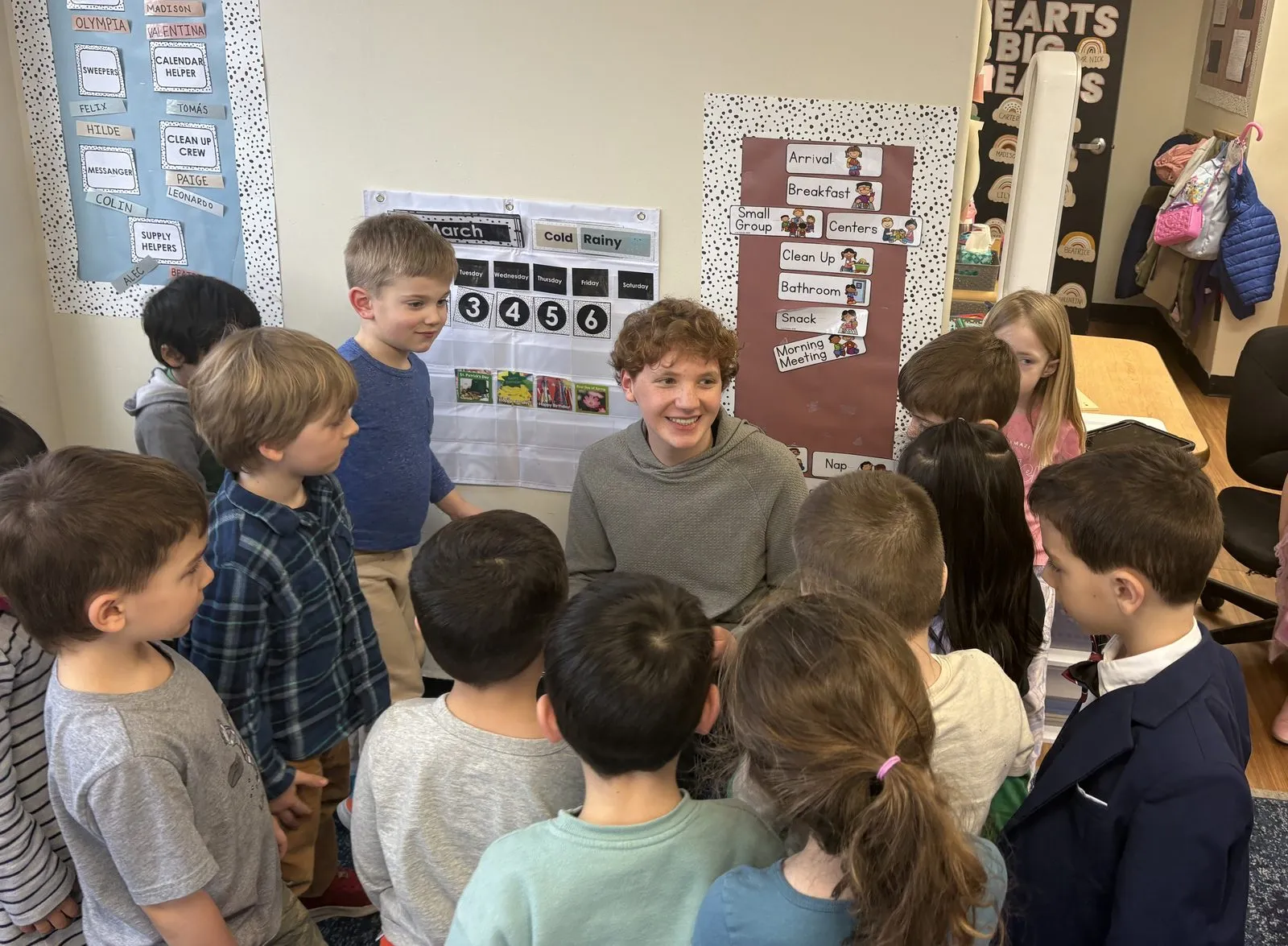 Zachary Penan smiling while surrounded by pre-k students during a mentoring visit at Little Friends in Greenwich.
