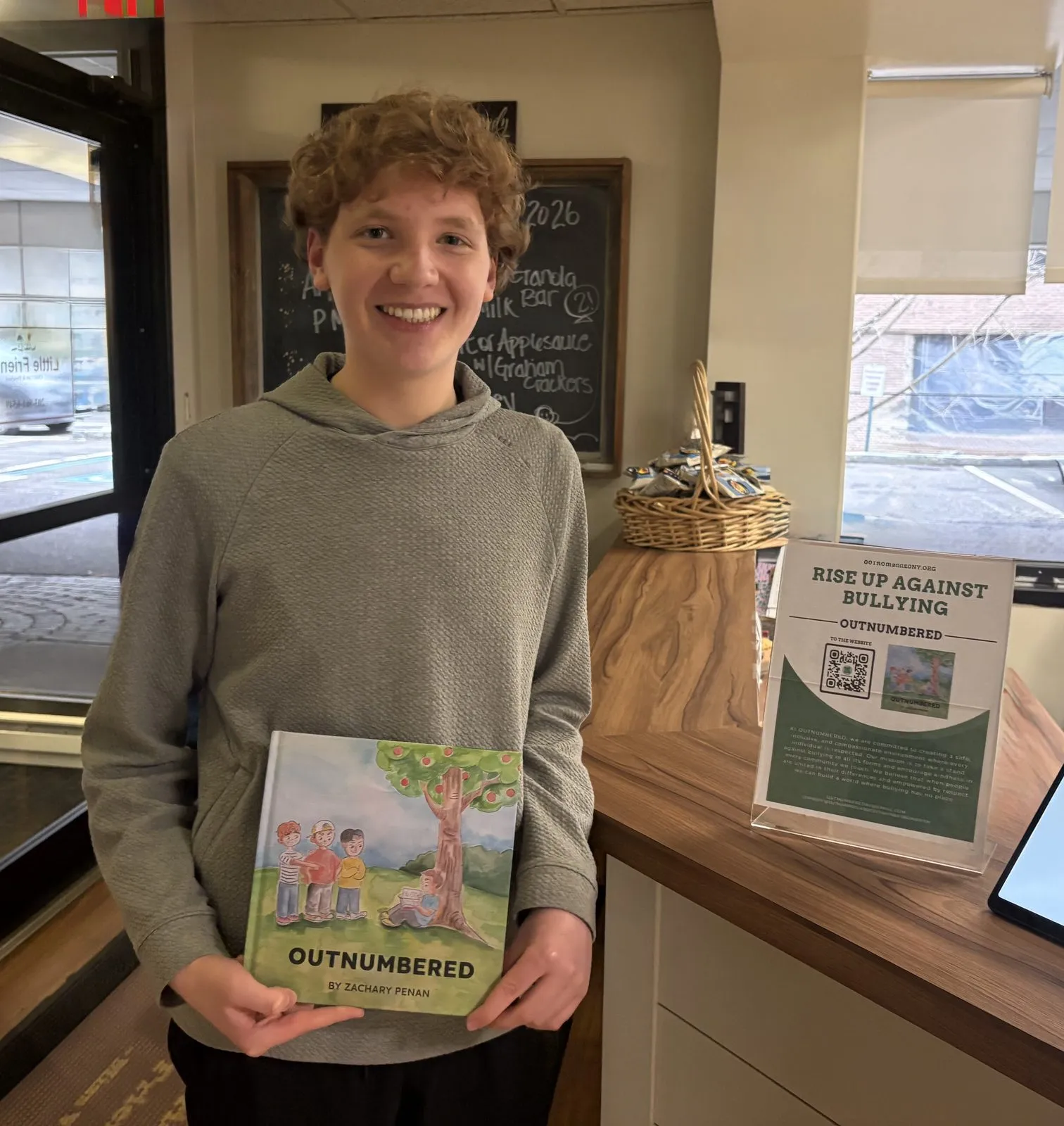 Zachary Penan holding a copy of Outnumbered next to an anti-bullying display during the Little Friends visit.