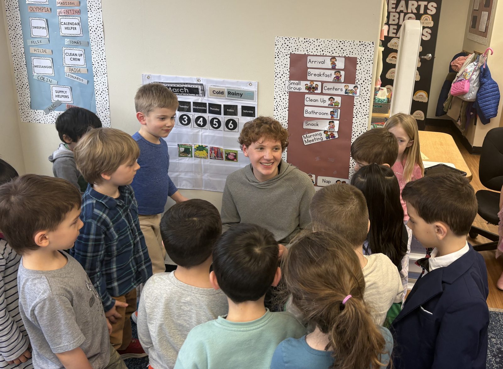 Zachary Penan smiling while surrounded by pre-k students during a mentoring visit at Little Friends in Greenwich.